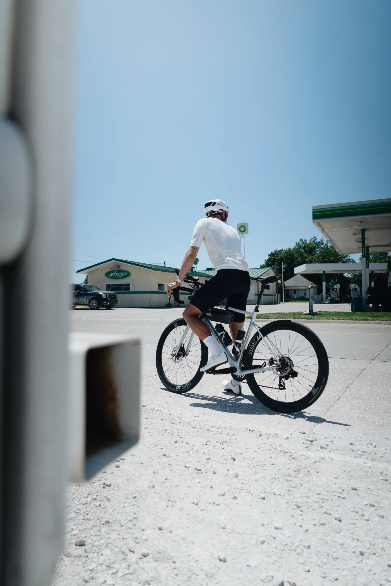 Peter Bolliger cycling past a petrol station