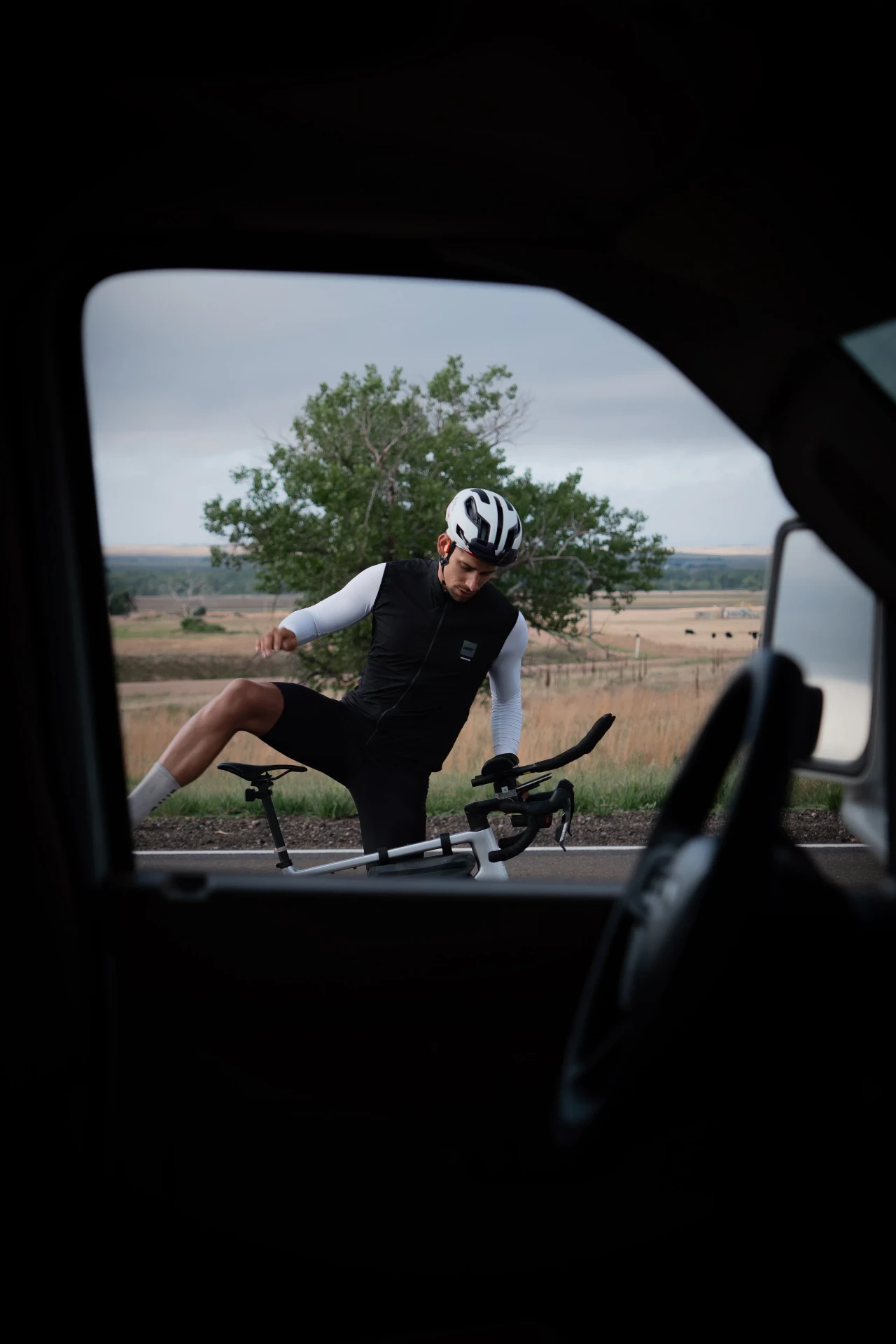Cyclist dismounting viewed through a car window