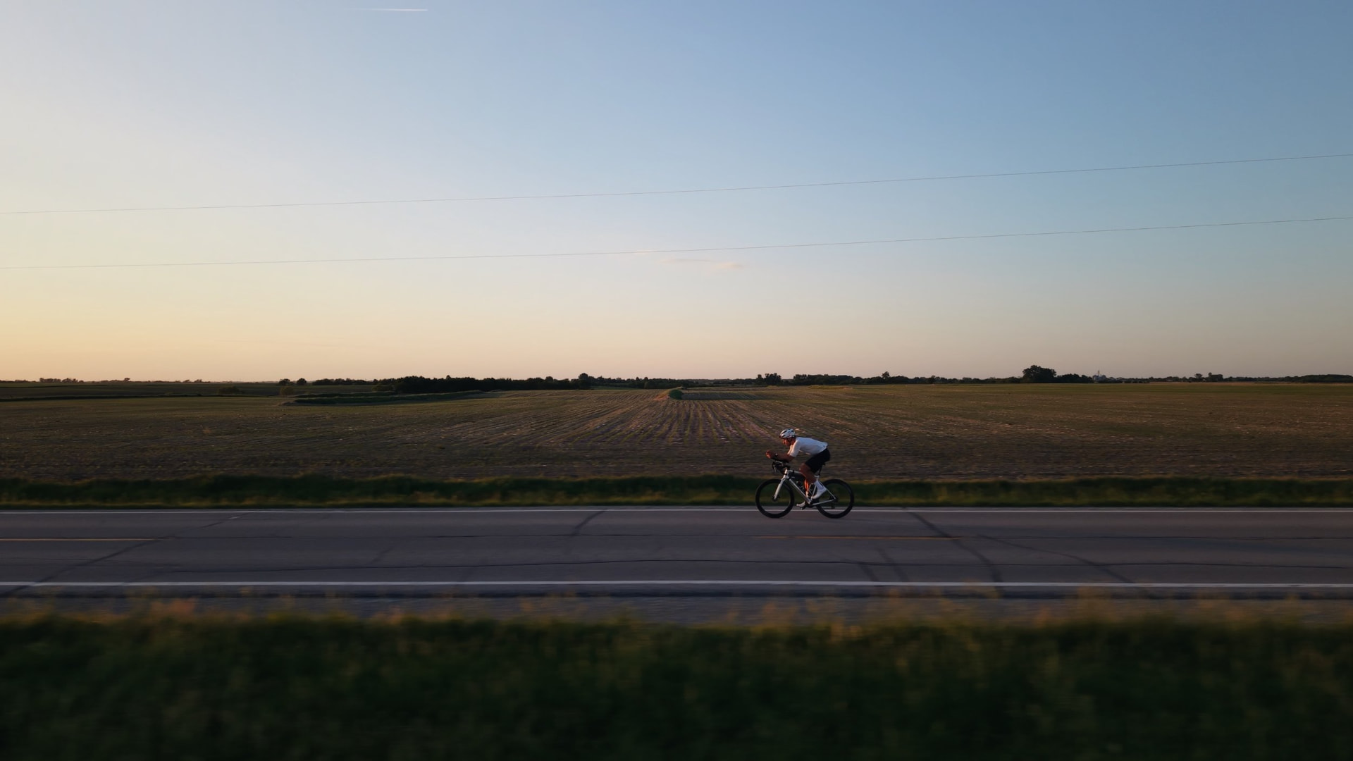 Cyclist riding through open fields at dusk