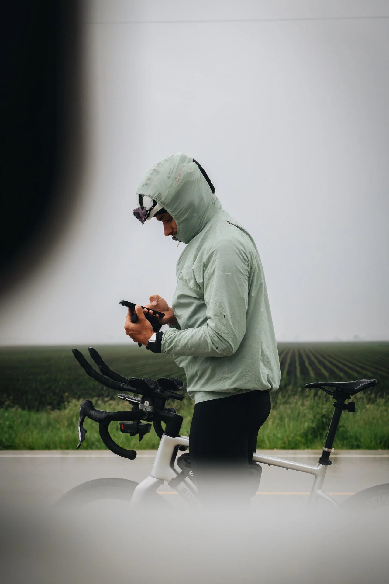 Peter Bolliger checking his phone in fog beside his bicycle