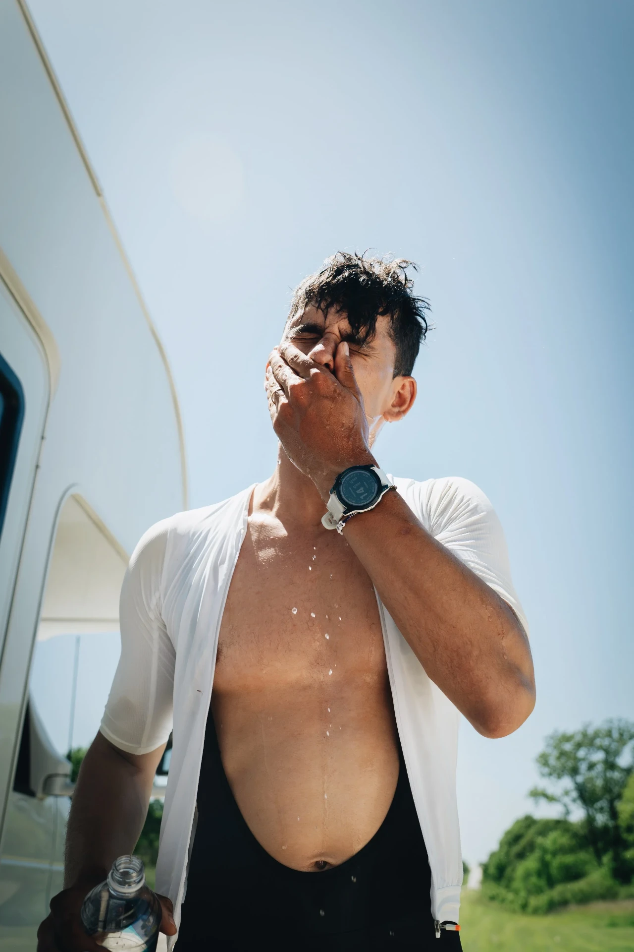 Peter Bolliger cooling his face with water beside a camper
